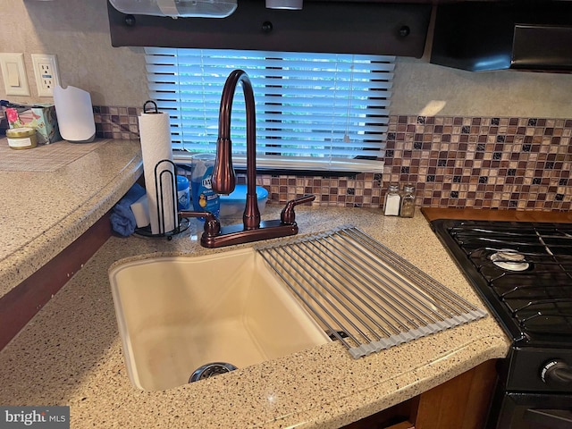 interior details featuring black range oven, sink, and backsplash