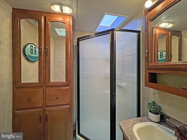 bathroom with a skylight, vanity, and an enclosed shower