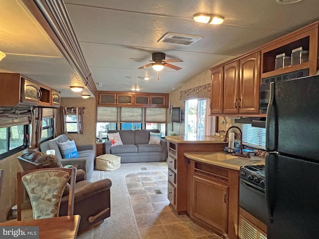 kitchen with ceiling fan, sink, vaulted ceiling, light carpet, and black appliances