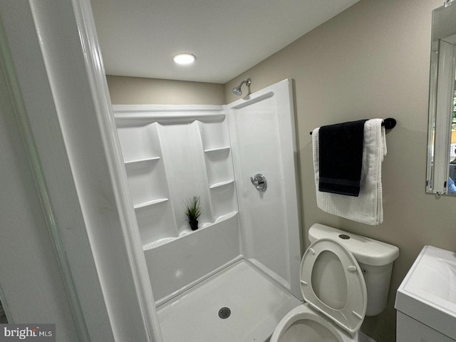 bathroom featuring walk in shower, vanity, and toilet