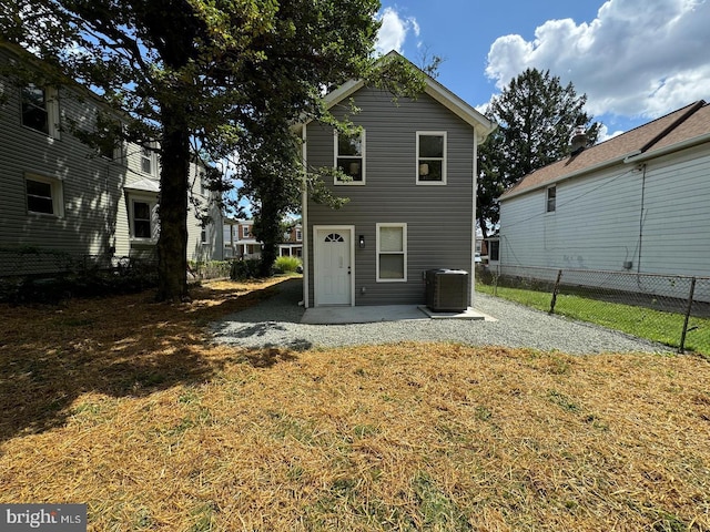 rear view of property featuring a yard, central AC unit, and a patio area