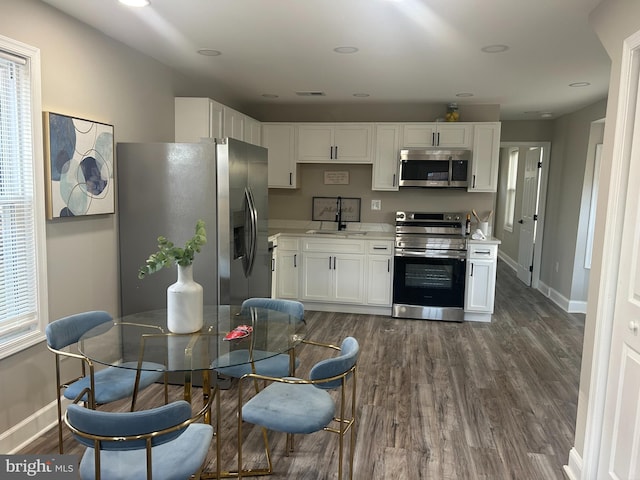 kitchen featuring appliances with stainless steel finishes, dark hardwood / wood-style floors, white cabinetry, and sink