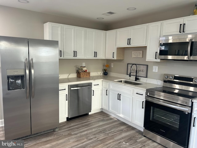 kitchen featuring stainless steel appliances, white cabinetry, dark wood-type flooring, and sink