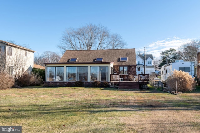 back of house featuring a deck, a lawn, and a sunroom