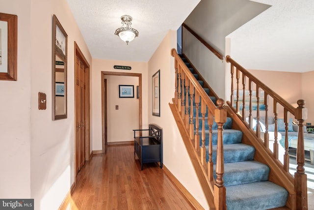 staircase with wood-type flooring and a textured ceiling