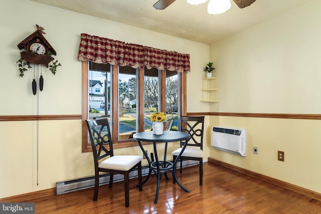 dining space with ceiling fan, hardwood / wood-style floors, a textured ceiling, and a baseboard heating unit