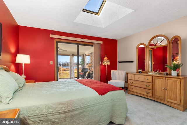 carpeted bedroom featuring access to outside, a textured ceiling, and a skylight