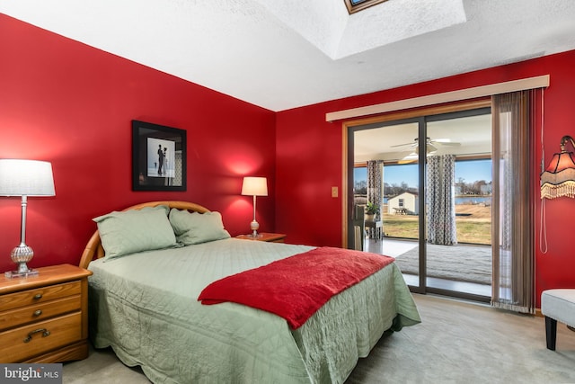 carpeted bedroom featuring access to exterior, a textured ceiling, and a skylight