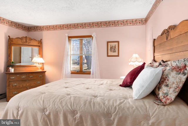 bedroom featuring a textured ceiling and a baseboard heating unit