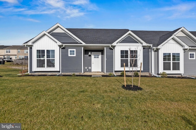 view of front of property with a shingled roof, a front lawn, and board and batten siding