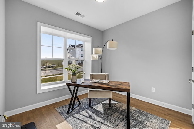 office space with wood finished floors, visible vents, and baseboards