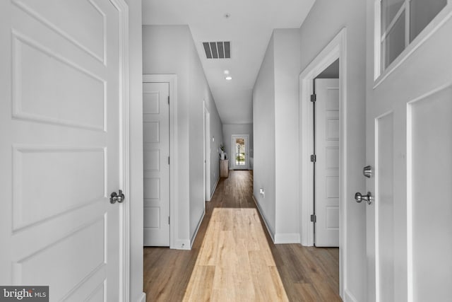 hall with recessed lighting, visible vents, baseboards, and wood finished floors