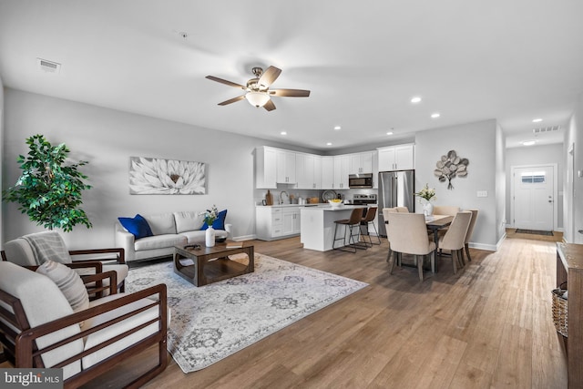 living area featuring light wood-style flooring, visible vents, ceiling fan, and recessed lighting