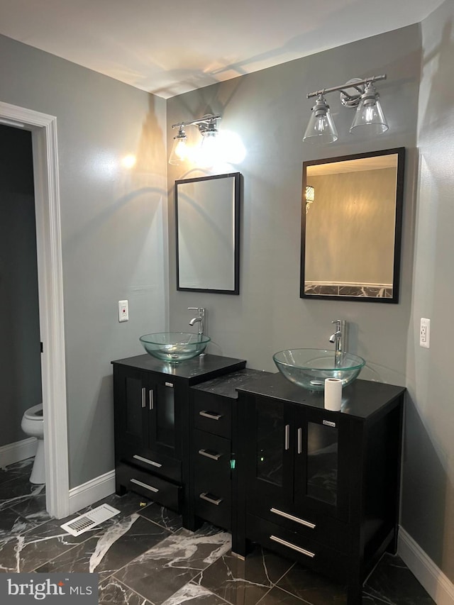 bathroom featuring marble finish floor, a sink, and baseboards