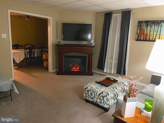 living room featuring a drop ceiling and carpet floors