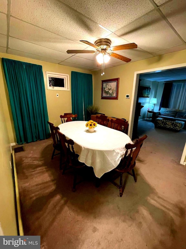 dining space with carpet flooring, ceiling fan, and a paneled ceiling