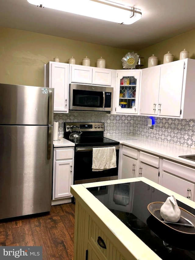 kitchen featuring tasteful backsplash, white cabinetry, dark wood-type flooring, and appliances with stainless steel finishes