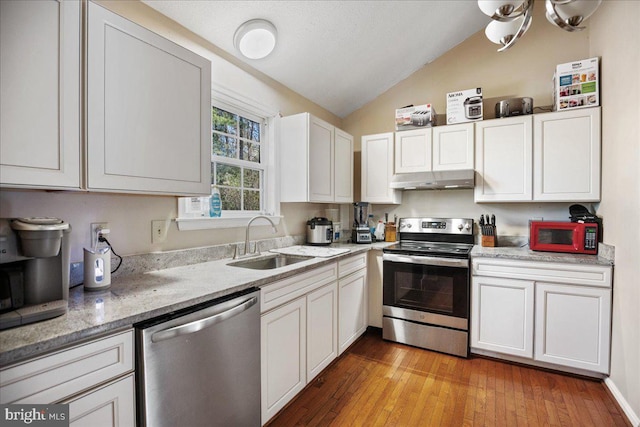 kitchen with lofted ceiling, sink, light wood-type flooring, white cabinetry, and stainless steel appliances