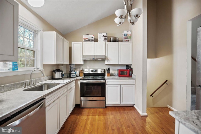 kitchen featuring appliances with stainless steel finishes, vaulted ceiling, sink, light hardwood / wood-style floors, and white cabinetry