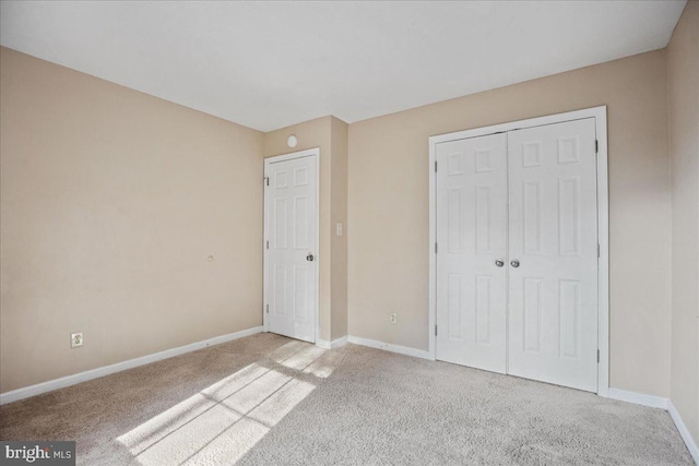 unfurnished bedroom with light colored carpet and a closet