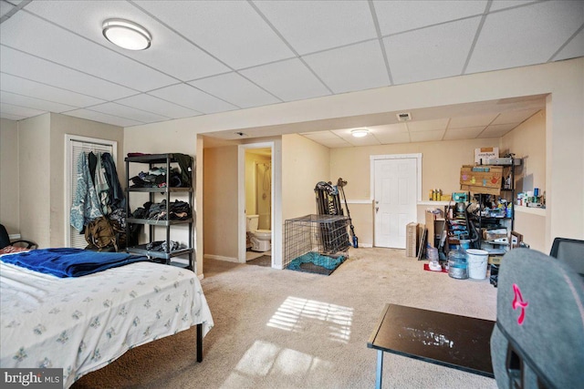 carpeted bedroom with a closet, ensuite bath, and a drop ceiling