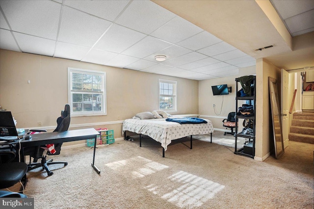 carpeted bedroom featuring a paneled ceiling and multiple windows