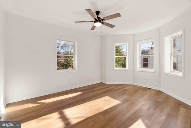 spare room featuring plenty of natural light, ceiling fan, and light wood-type flooring