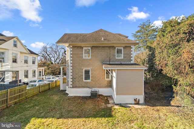 rear view of property with a lawn and central AC