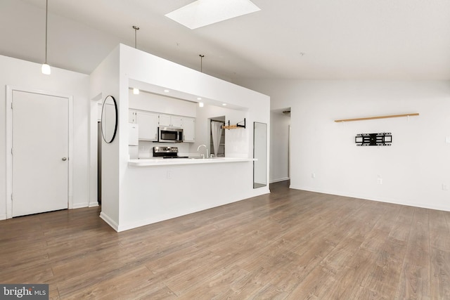 unfurnished living room with high vaulted ceiling, a skylight, light hardwood / wood-style flooring, and sink