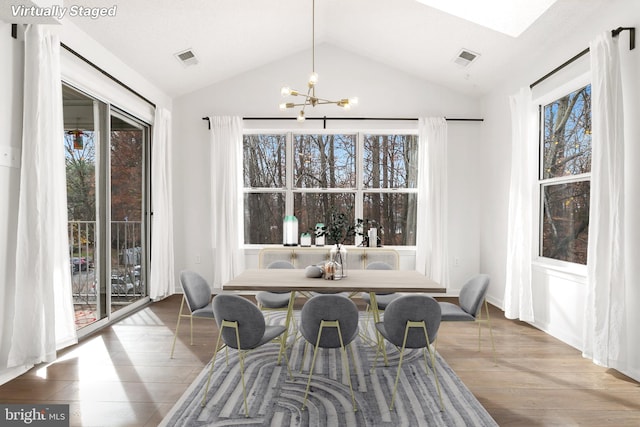 dining area with wood-type flooring, vaulted ceiling, and a notable chandelier