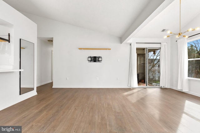 unfurnished living room featuring hardwood / wood-style flooring, lofted ceiling, and a chandelier