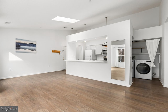 unfurnished living room featuring washer / dryer, lofted ceiling with skylight, and hardwood / wood-style floors