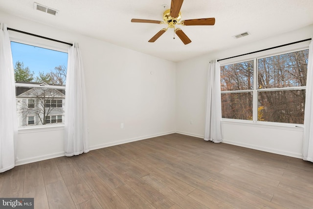 spare room featuring hardwood / wood-style flooring, ceiling fan, and a healthy amount of sunlight