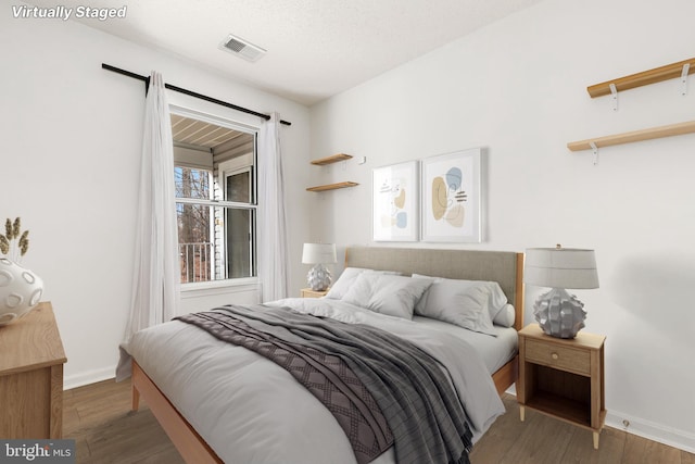 bedroom with a textured ceiling and dark hardwood / wood-style flooring