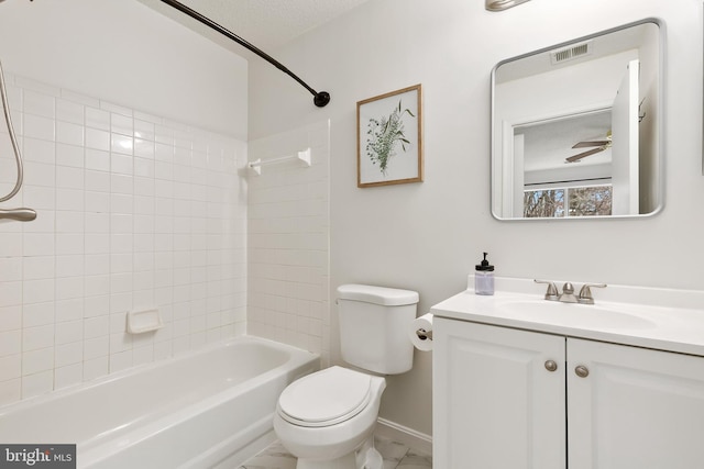 full bathroom with tiled shower / bath, vanity, a textured ceiling, and toilet