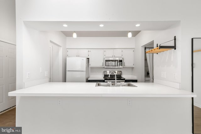 kitchen with sink, kitchen peninsula, dark wood-type flooring, and appliances with stainless steel finishes