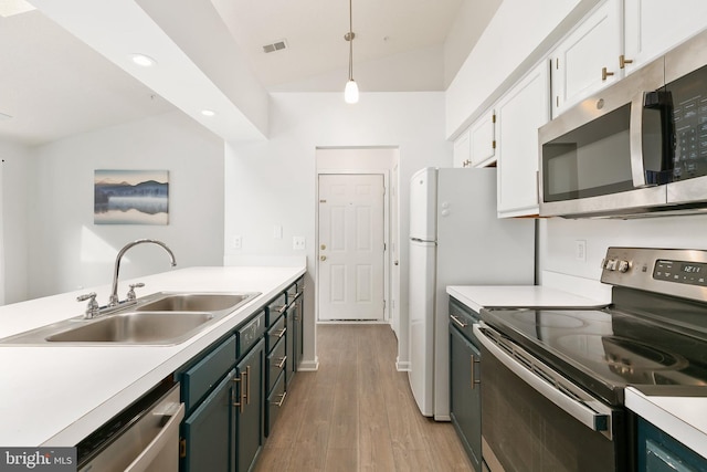 kitchen featuring stainless steel appliances, sink, decorative light fixtures, white cabinetry, and lofted ceiling