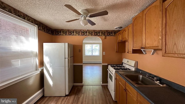 kitchen featuring ceiling fan, sink, hardwood / wood-style floors, a textured ceiling, and white appliances