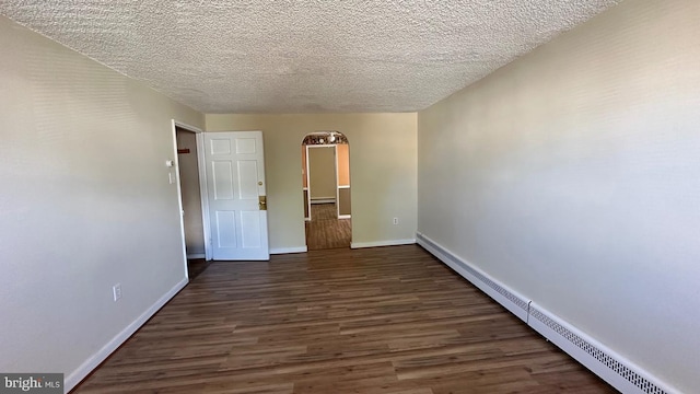 unfurnished room with a textured ceiling, dark hardwood / wood-style flooring, and baseboard heating