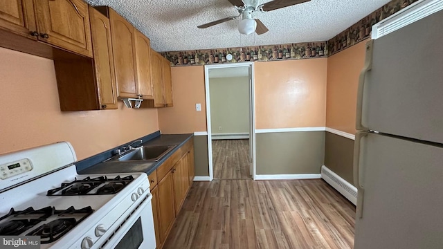 kitchen with light hardwood / wood-style floors, white appliances, a textured ceiling, and a baseboard heating unit