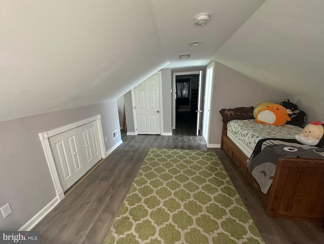 bedroom with vaulted ceiling, a closet, and dark hardwood / wood-style floors