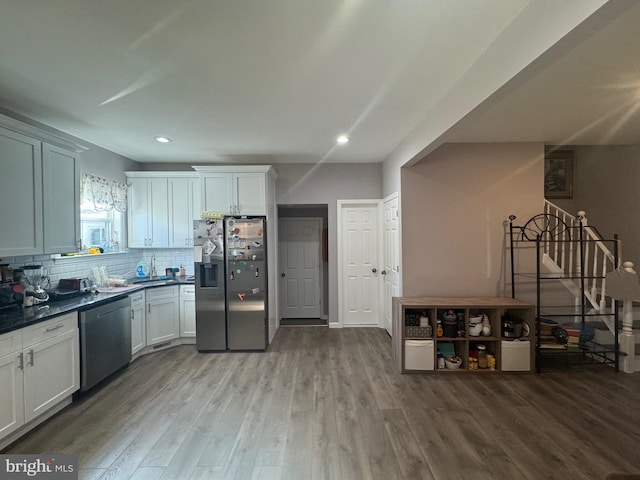 kitchen featuring tasteful backsplash, white cabinets, stainless steel appliances, and light wood-type flooring