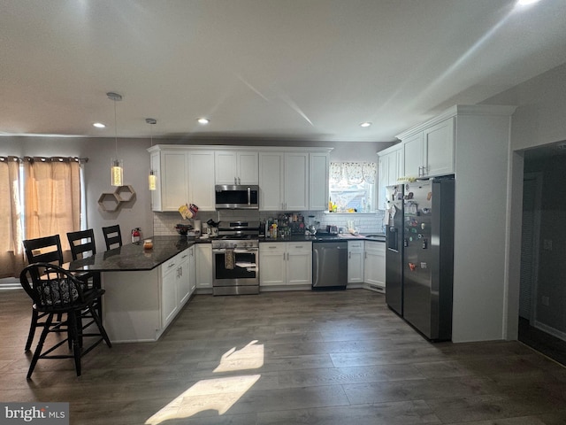 kitchen featuring white cabinets, appliances with stainless steel finishes, dark hardwood / wood-style flooring, and pendant lighting