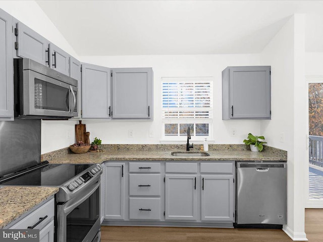 kitchen with gray cabinetry, lofted ceiling, sink, and appliances with stainless steel finishes