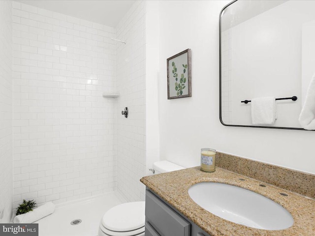 bathroom featuring vanity, toilet, and tiled shower