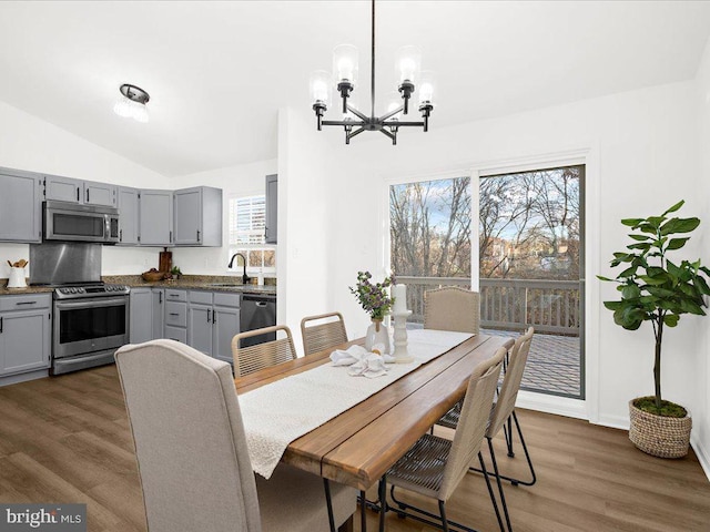 dining area featuring dark hardwood / wood-style flooring, a notable chandelier, lofted ceiling, and sink