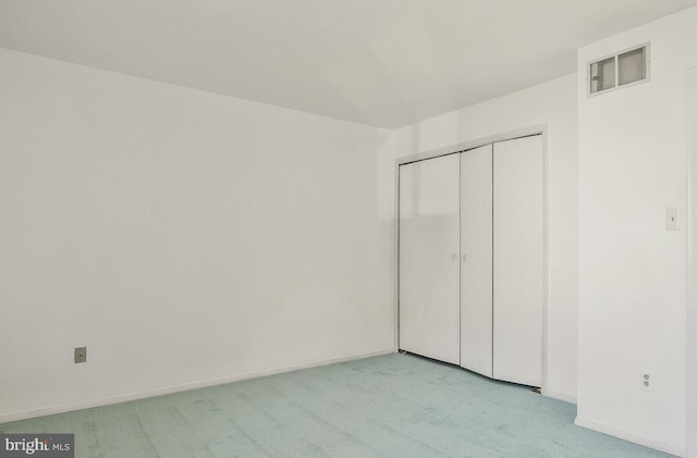 unfurnished bedroom featuring light carpet and a closet