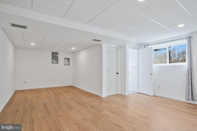 basement featuring light wood-type flooring and a paneled ceiling