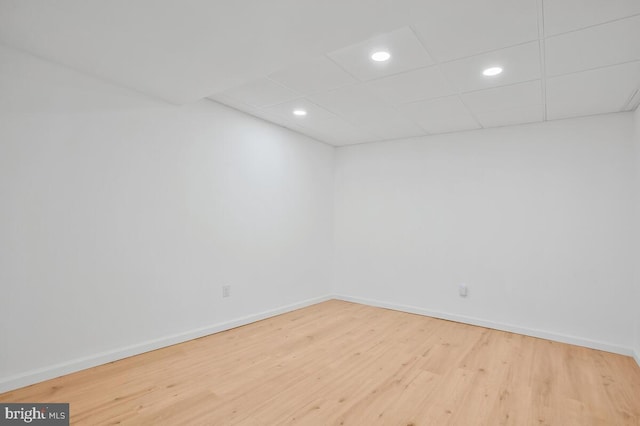 unfurnished room with a drop ceiling and wood-type flooring