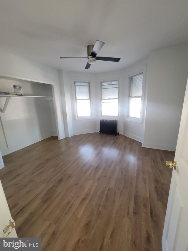 unfurnished living room with radiator, dark hardwood / wood-style floors, and ceiling fan